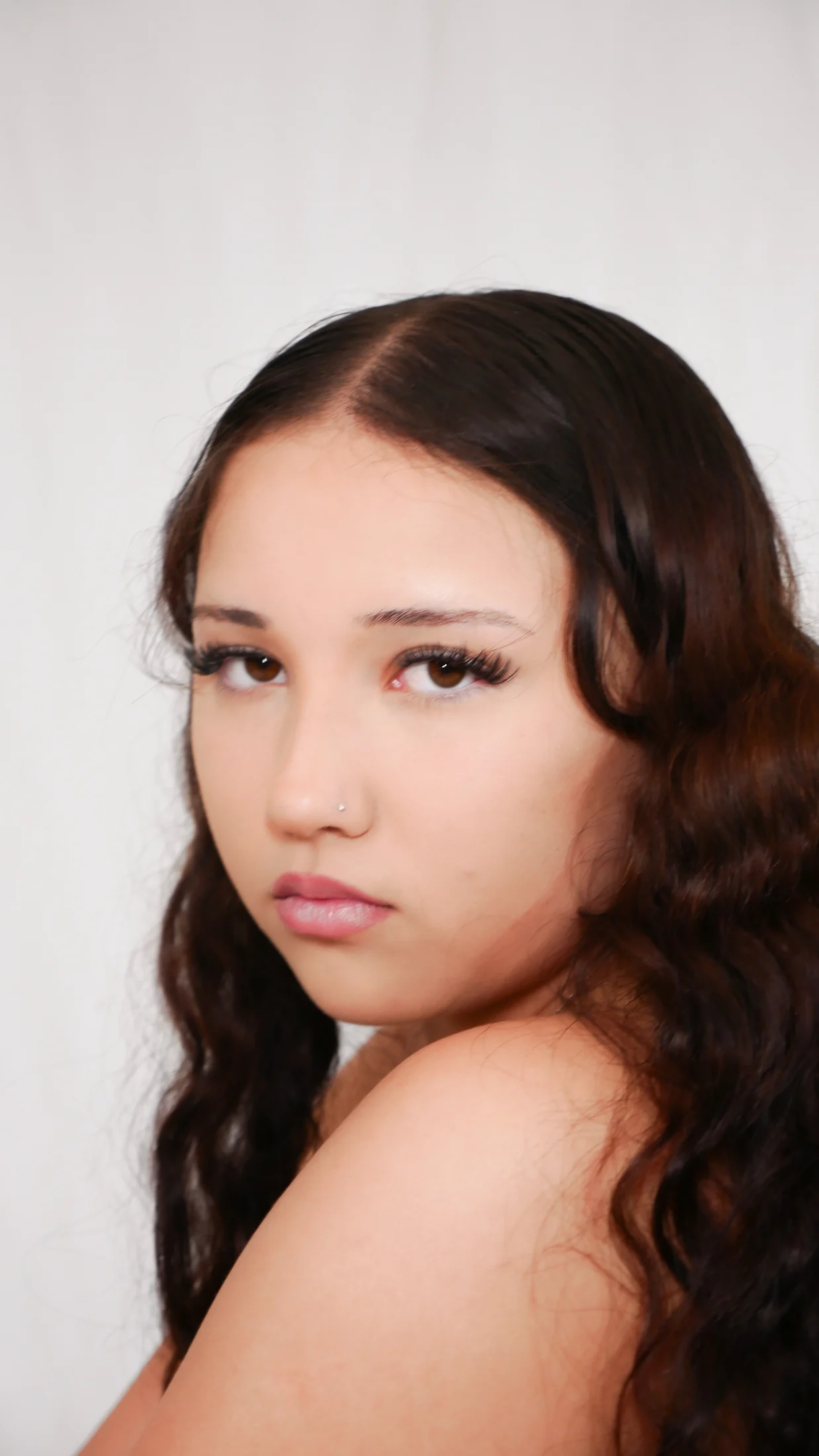 Close RAW Form portrait of a young woman with long dark hair, in soft studio light