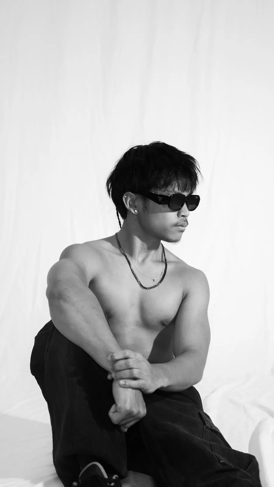Creative portrait of a young man in sunglasses and cargo pants on the white sweep at Birdcage Studios