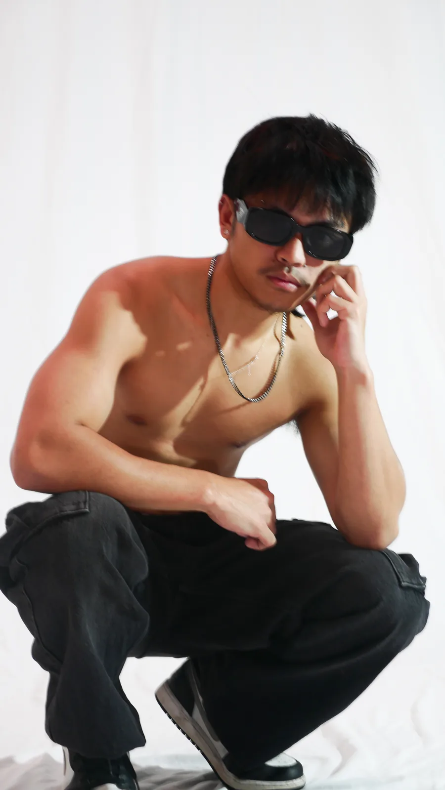 Creative portrait of a young man in sunglasses and cargo pants on the white sweep at Birdcage Studios