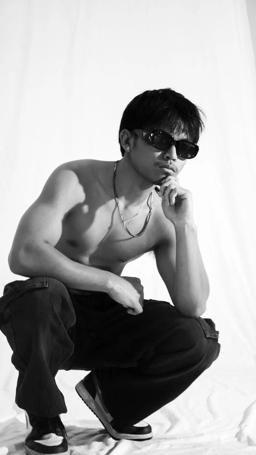 Creative portrait of a young man in sunglasses and cargo pants on the white sweep at Birdcage Studios