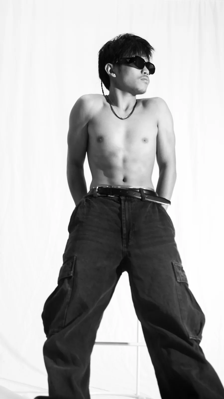 Creative portrait of a young man in sunglasses and cargo pants on the white sweep at Birdcage Studios