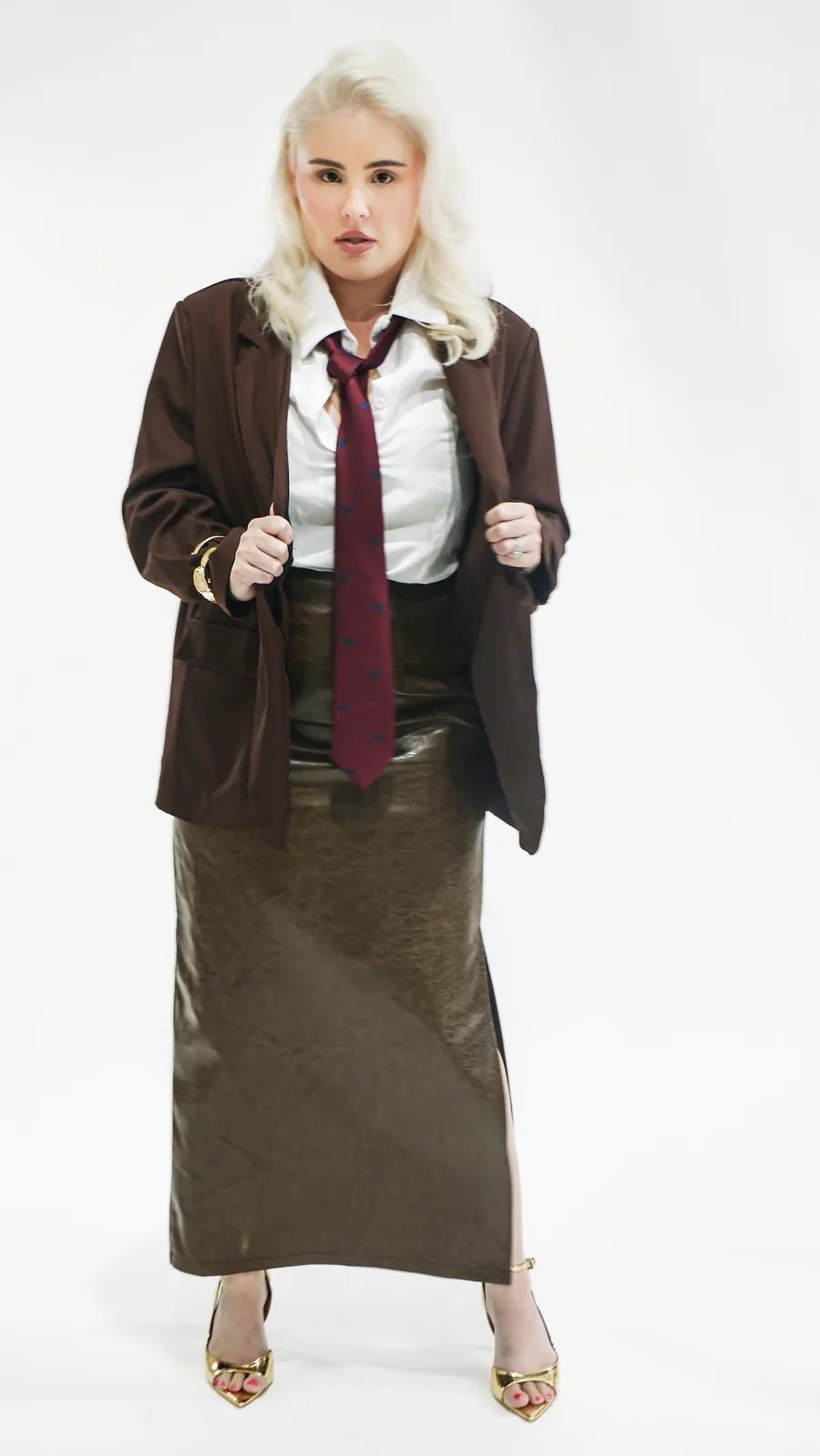 Editorial portrait of a woman in a brown blazer and tie on the white sweep at Birdcage Studios